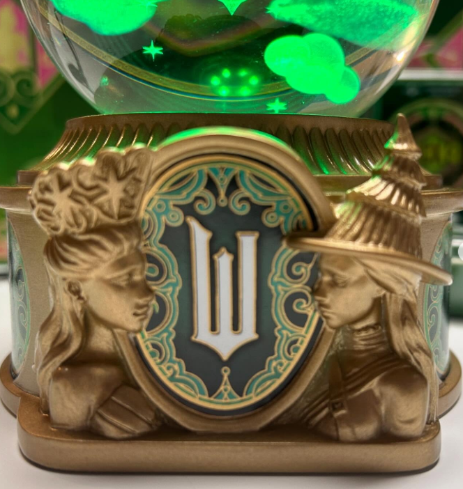 Close-up detail from the Wicked x Scentsy Emerald City Warmer showing sculpted figures of Glinda and Elphaba on the base, representing friendship and magic in the Land of Oz.