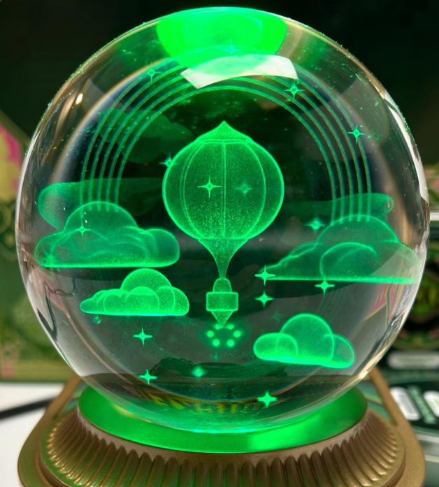 The glowing hot air balloon and rainbow cloud design inside the Wicked x Scentsy Emerald City Warmer’s orb — a stunning green light display inspired by the world of Wicked.