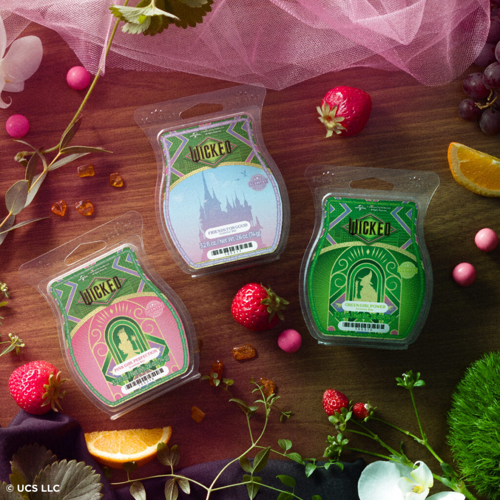 Flat lay of the Wicked x Scentsy wax bar trio — Friends for Good, Green Girl Power, and Fierce Girl Protection — surrounded by fruit, flowers, and colorful accents that highlight their unique fragrance blends.