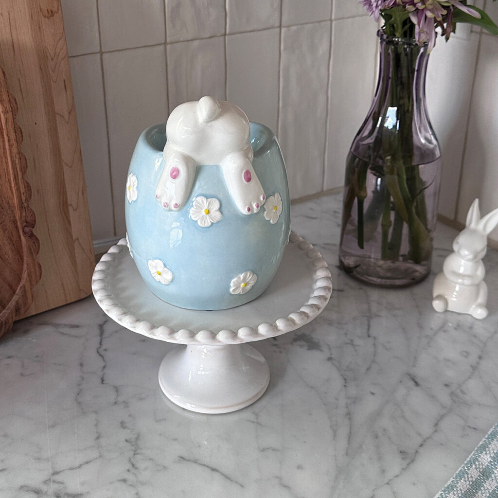 A blue warmer with white flowers hold up the silly bunny while he looks for goodies.