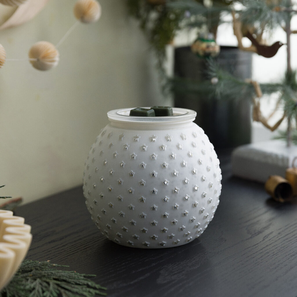 The Snowdrop Warmer by Scentsy turned off, showing its soft white hobnail-style glass covered in tiny star details. Styled with winter greenery and cozy holiday decor — perfect neutral home piece that blends into any Christmas setup.