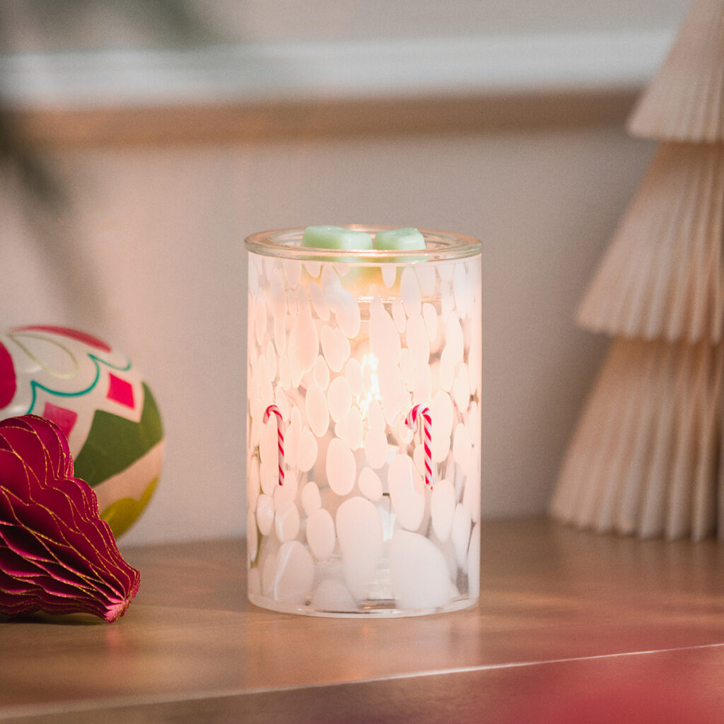 Scentsy Candy Cane Confetti Glass Warmer glowing with white frosted glass and tiny candy cane accents. A cozy and festive warmer that brings cheerful holiday sparkle to your space.