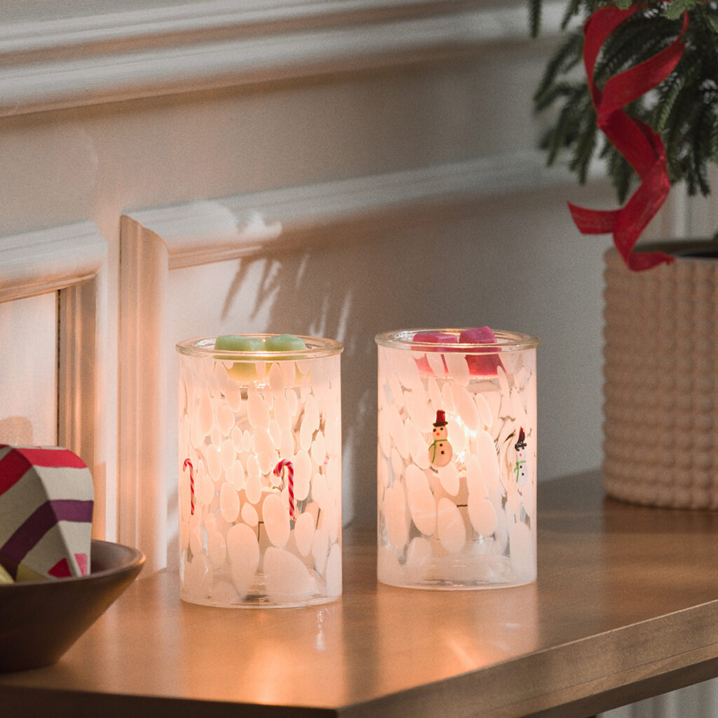 Side-by-side view of Scentsy’s Candy Cane and Snowman Confetti Glass Warmers, softly glowing with festive wax melts. The perfect matching set for a cozy, modern holiday display.