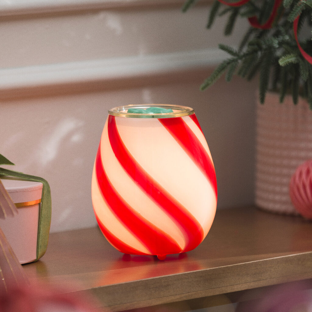 Scentsy Peppermint Swirl Warmer shaped like a classic candy cane treat, glowing red and white with swirling stripes. Adds a fun, nostalgic pop of Christmas cheer to any room.
