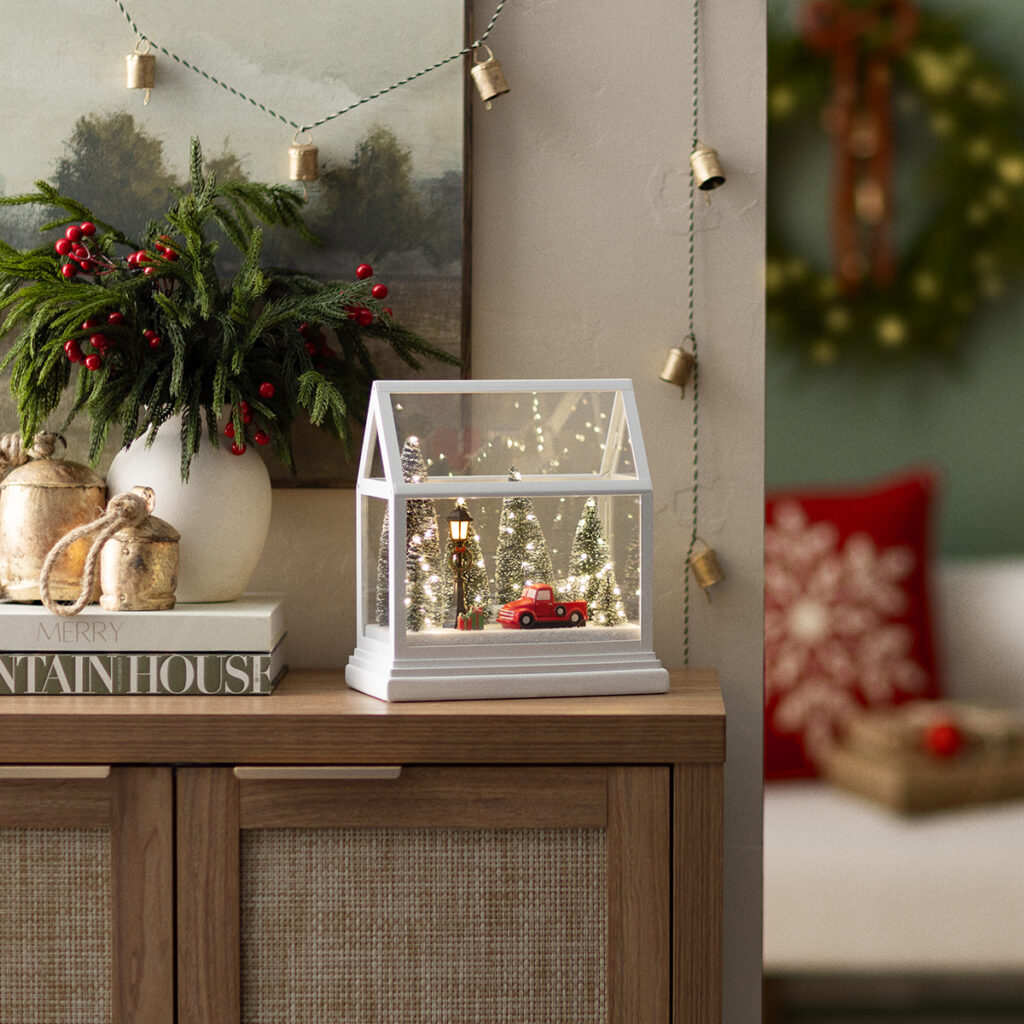 The Dashing Through the Pines Limited Edition Holiday Warmer by Scentsy styled in a cozy living room setup with holiday greenery, gold bells, and warm farmhouse Christmas decor — featuring a red truck, snowy trees, and twinkling lights.