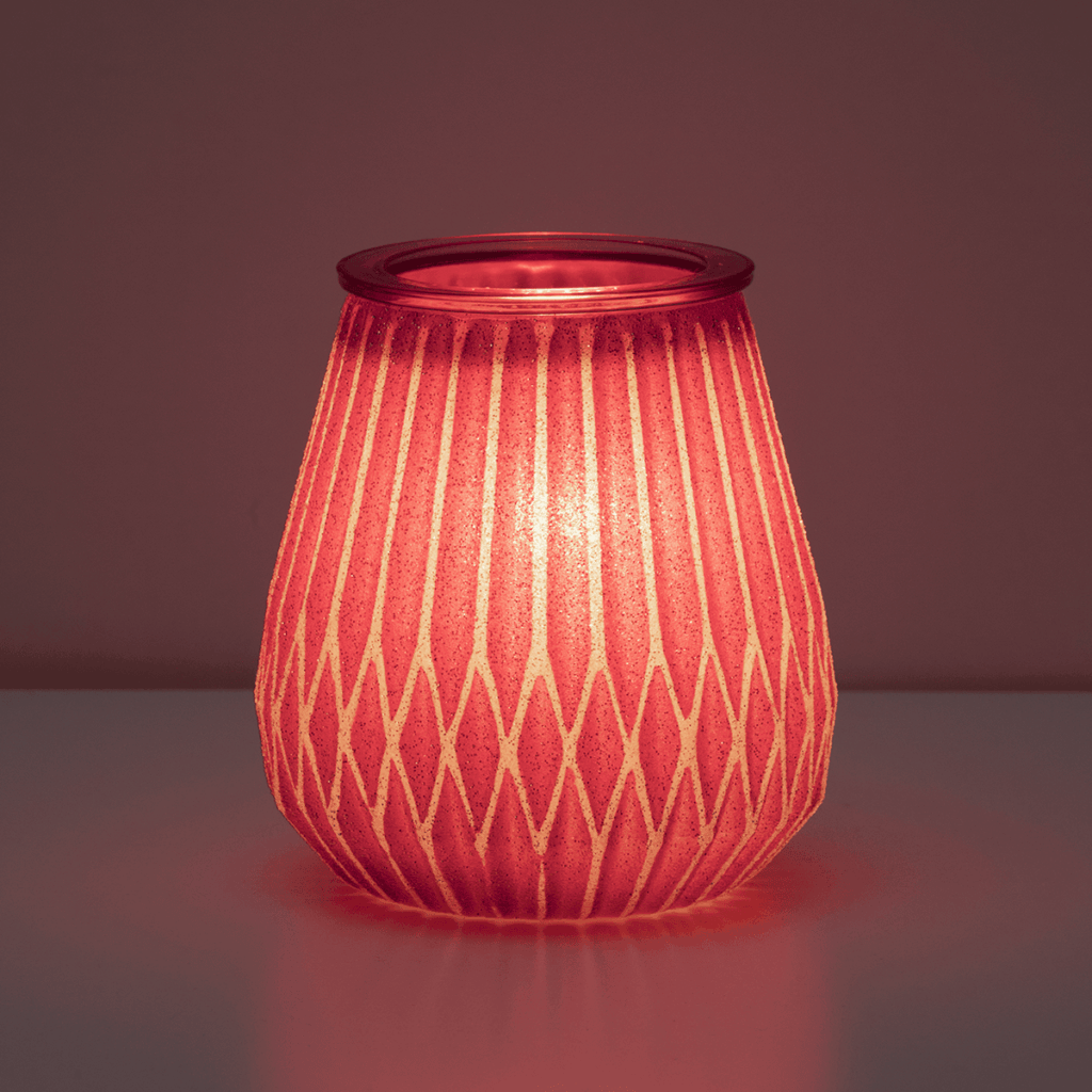 The Frosted in Fuchsia by Scentsy glowing warmly in pink, showing off its glittering pattern. Adds a cozy and modern holiday touch to your home