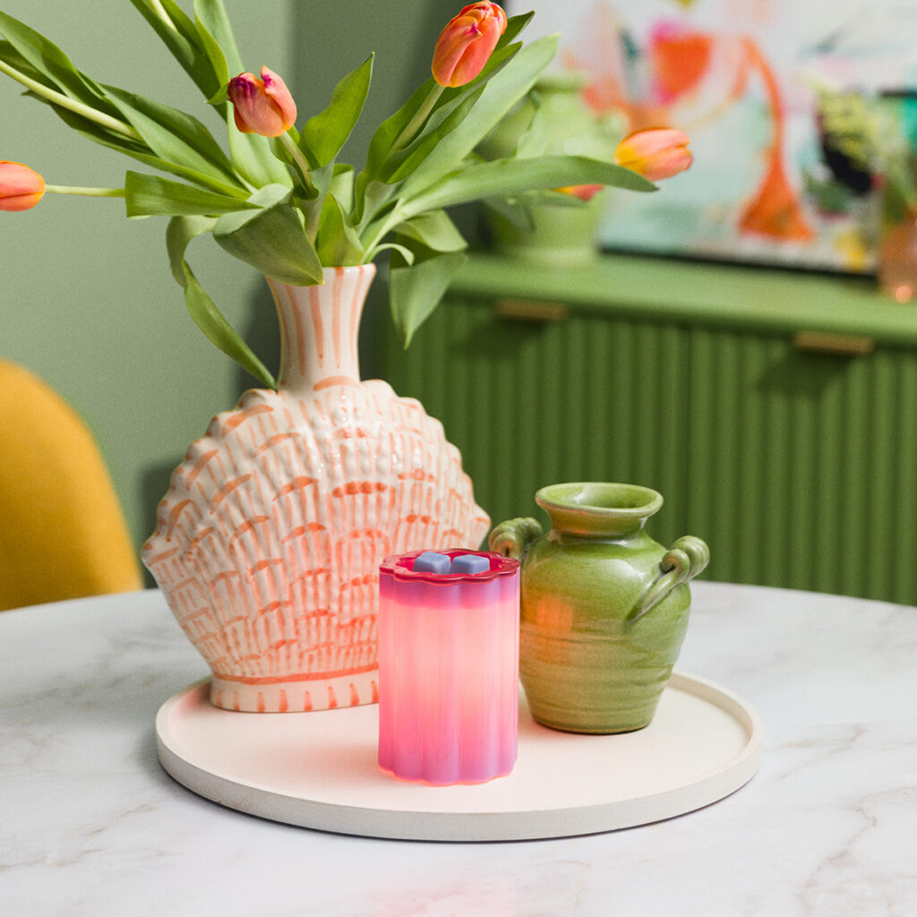 Bloomie Purple Scentsy warmer lit and glowing in a cozy home setting