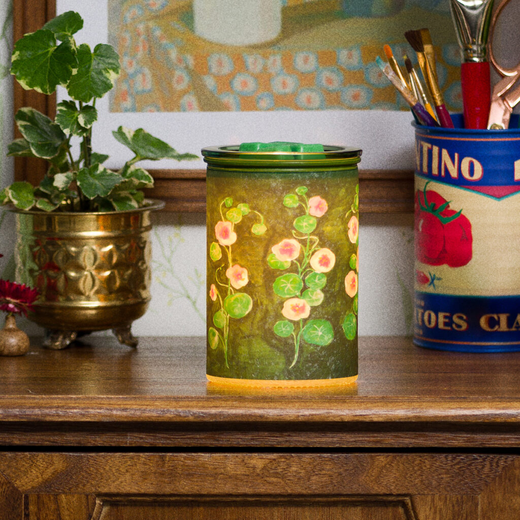 Garden Whimsy Scentsy warmer featuring a hand-painted floral design with soft green tones, glowing on a wooden shelf.