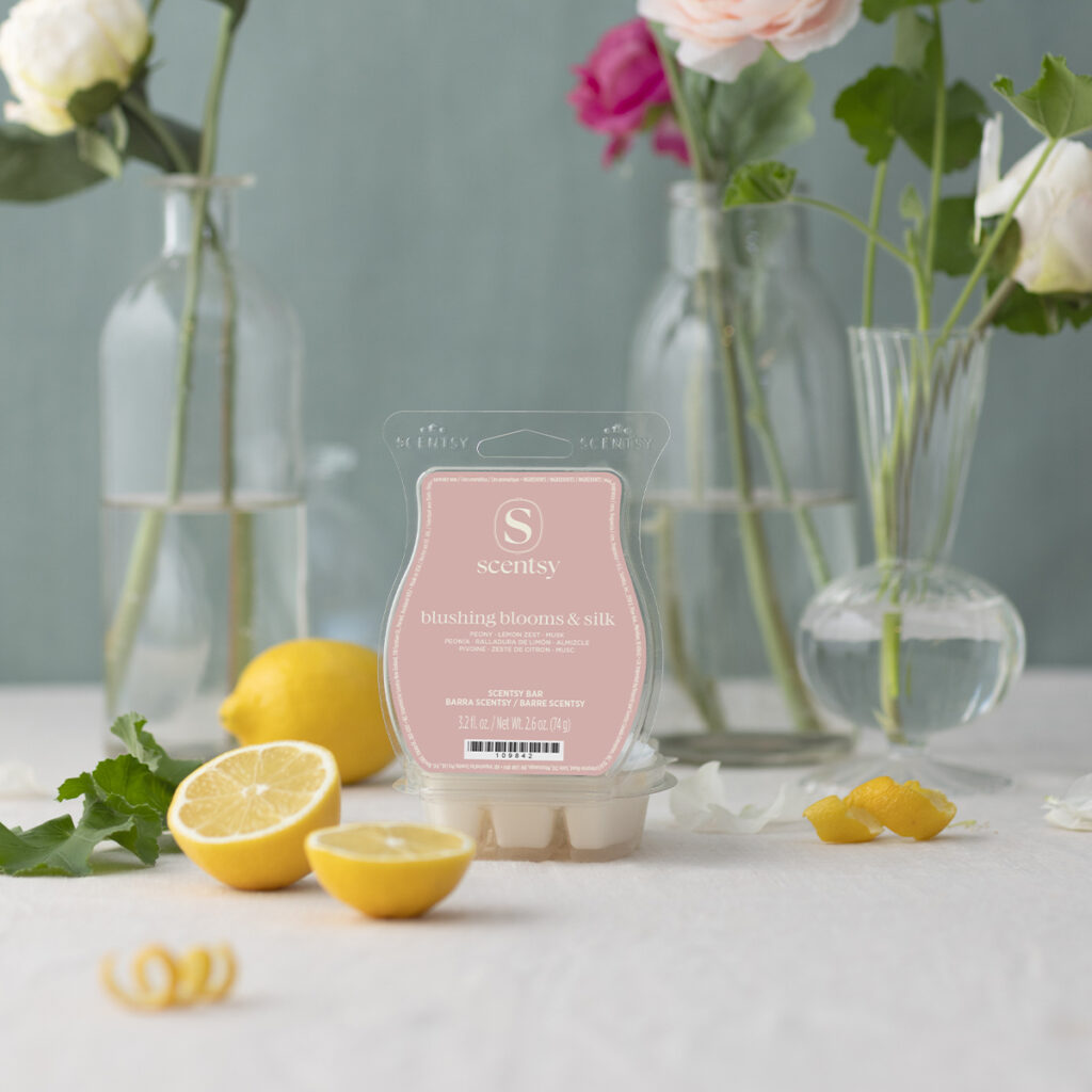 Scentsy Blushing Blooms & Silk wax bar surrounded by flowers and lemons on a light tabletop.