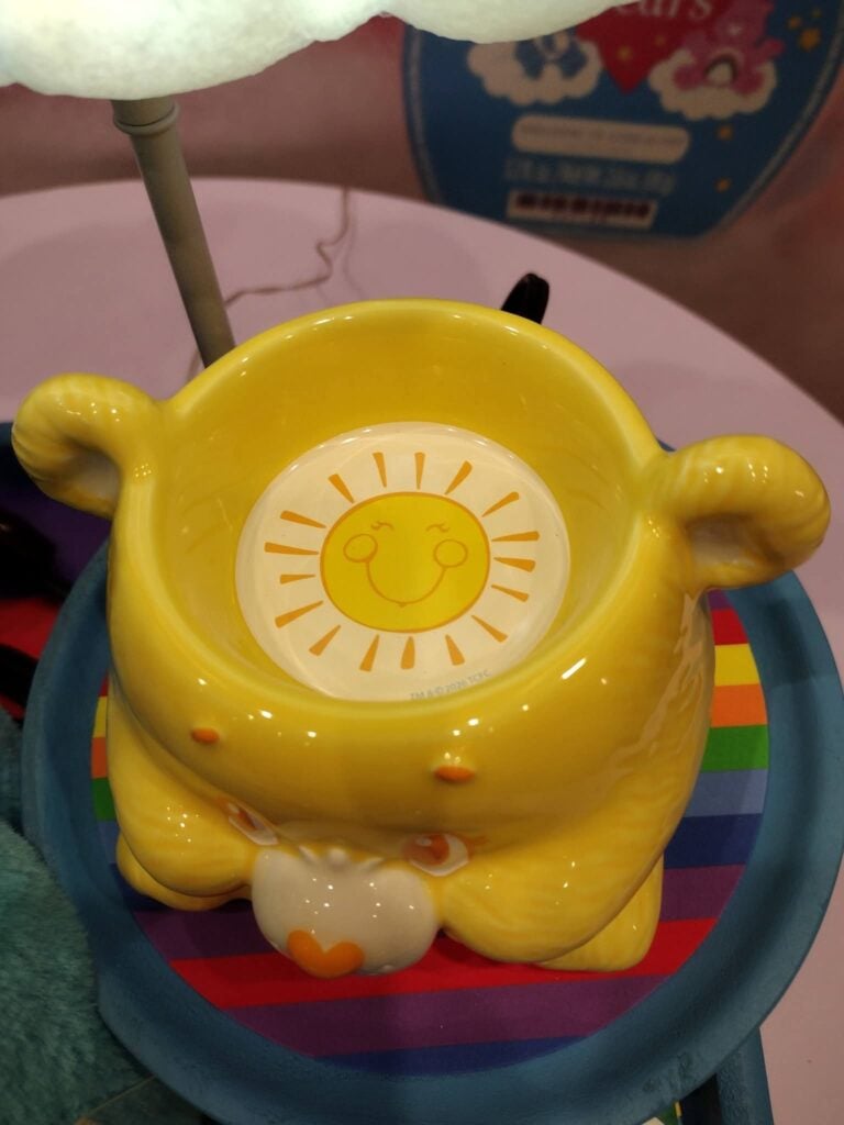 Close-up of the yellow Scentsy Care Bears Funshine Bear Warmer with a smiling sun design inside the warming dish