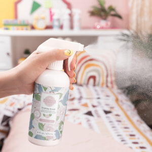 Scentsy Fresh fabric spray in Magnolia Linen being sprayed onto a couch to eliminate odors and freshen upholstery.
