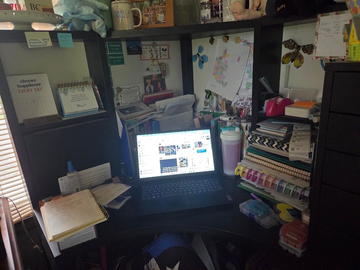 Organized home office workspace with a laptop, planners, notebooks, office supplies, and business organization tools arranged on a corner desk.