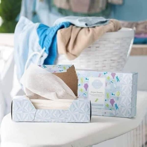 Open box of Scentsy Dryer Sheets in the Clothesline fragrance beside a second box with freshly washed laundry in the background.