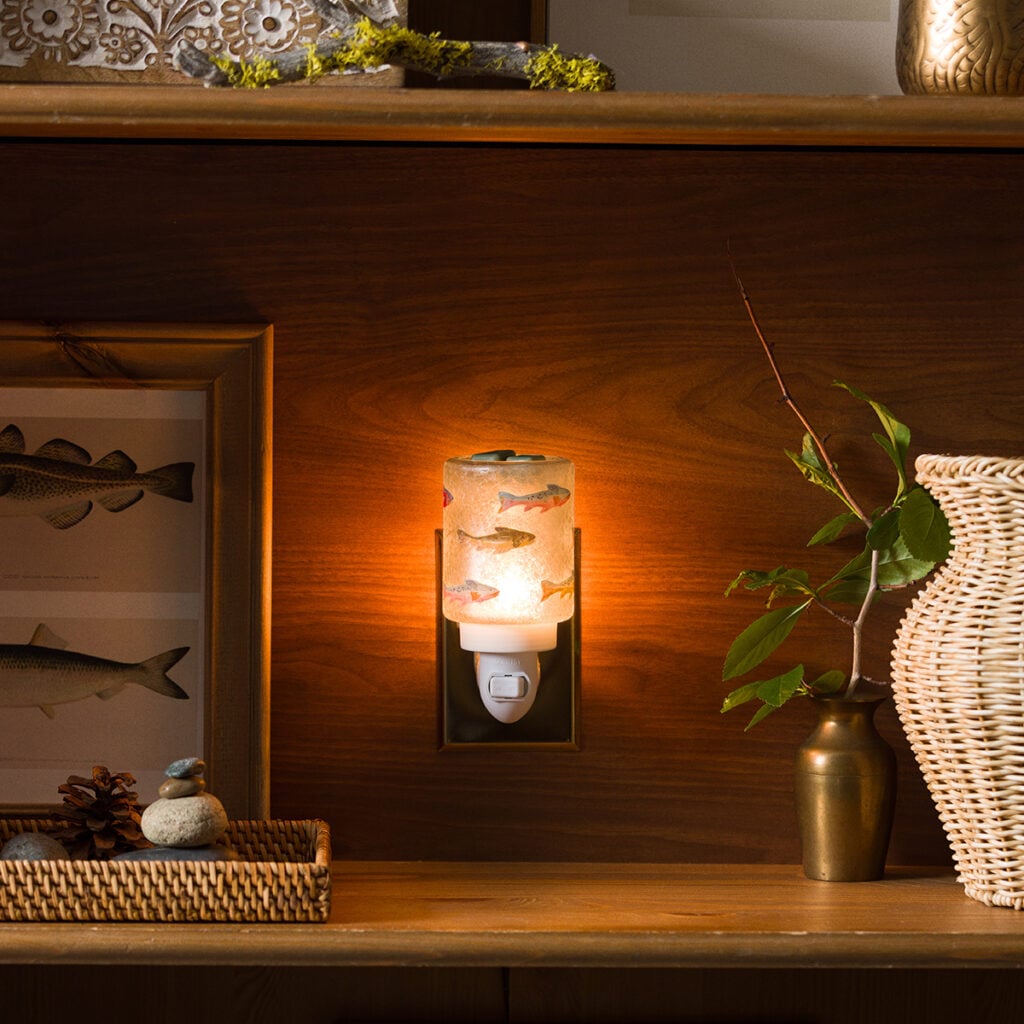 Silver Fins Scentsy Mini Warmer featuring colorful fish artwork glowing while plugged into a wall outlet.