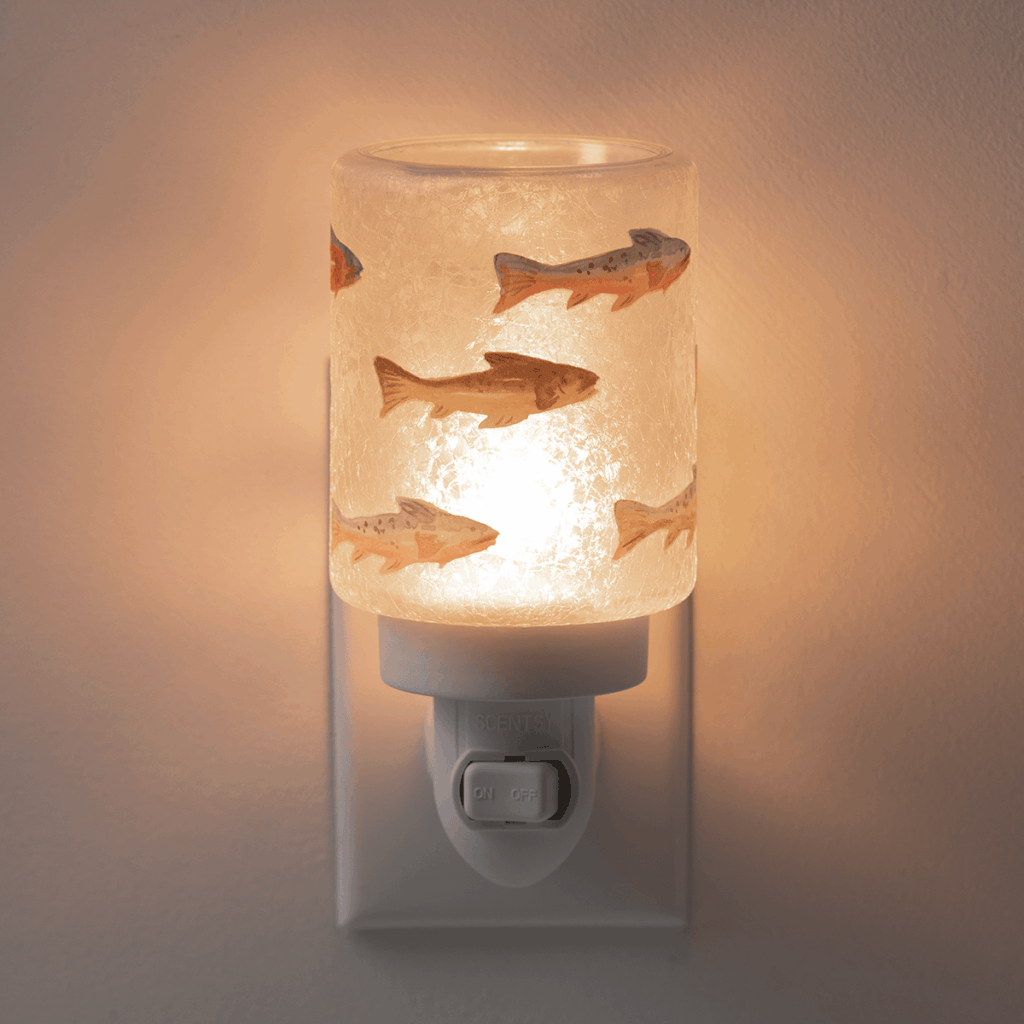 Silver Fins Scentsy Mini Warmer glowing while plugged into a wall outlet, featuring colorful fish artwork on frosted glass.