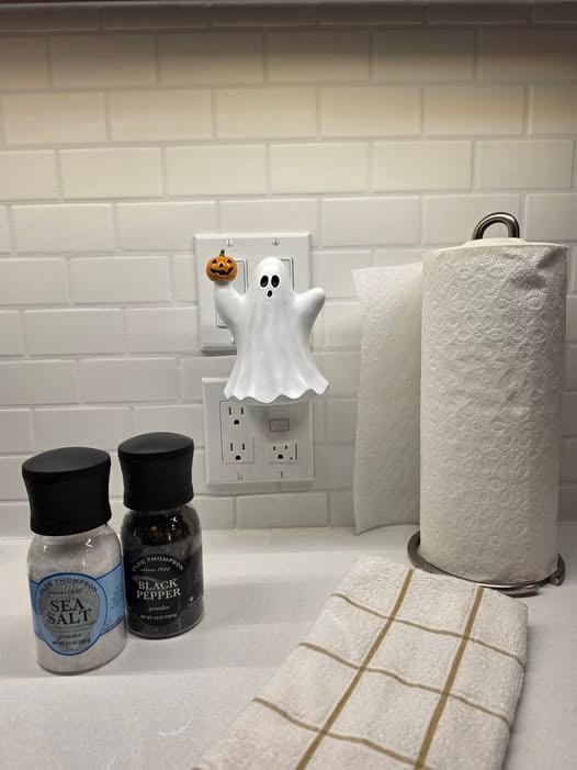 Pumpkin Spirit Scentsy Air Mini glowing in a kitchen outlet with a smiling ghost and tiny pumpkin Halloween design.