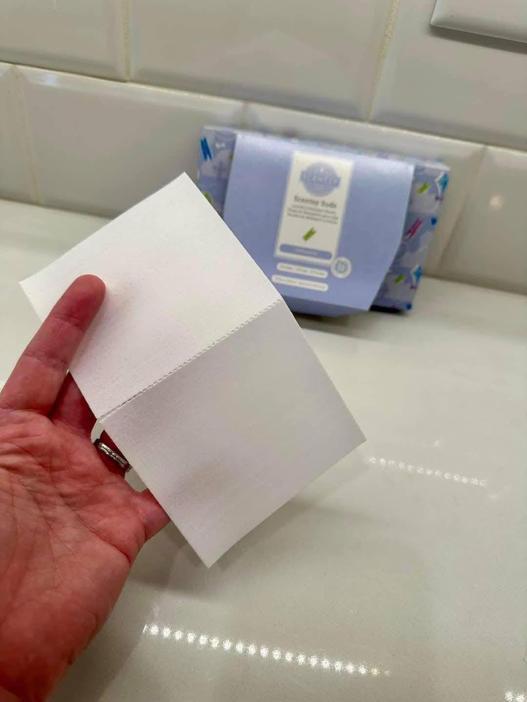 Scentsy Suds laundry detergent sheets shown by hand with the package in the background
