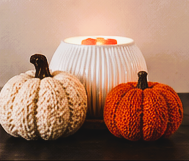 White Fluted warmer with a cream knit pumpkin and an orange knit pumpkin