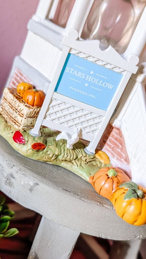 Close-up of the Welcome to Stars Hollow Scentsy Warmer sign surrounded by pumpkins and fall leaves.