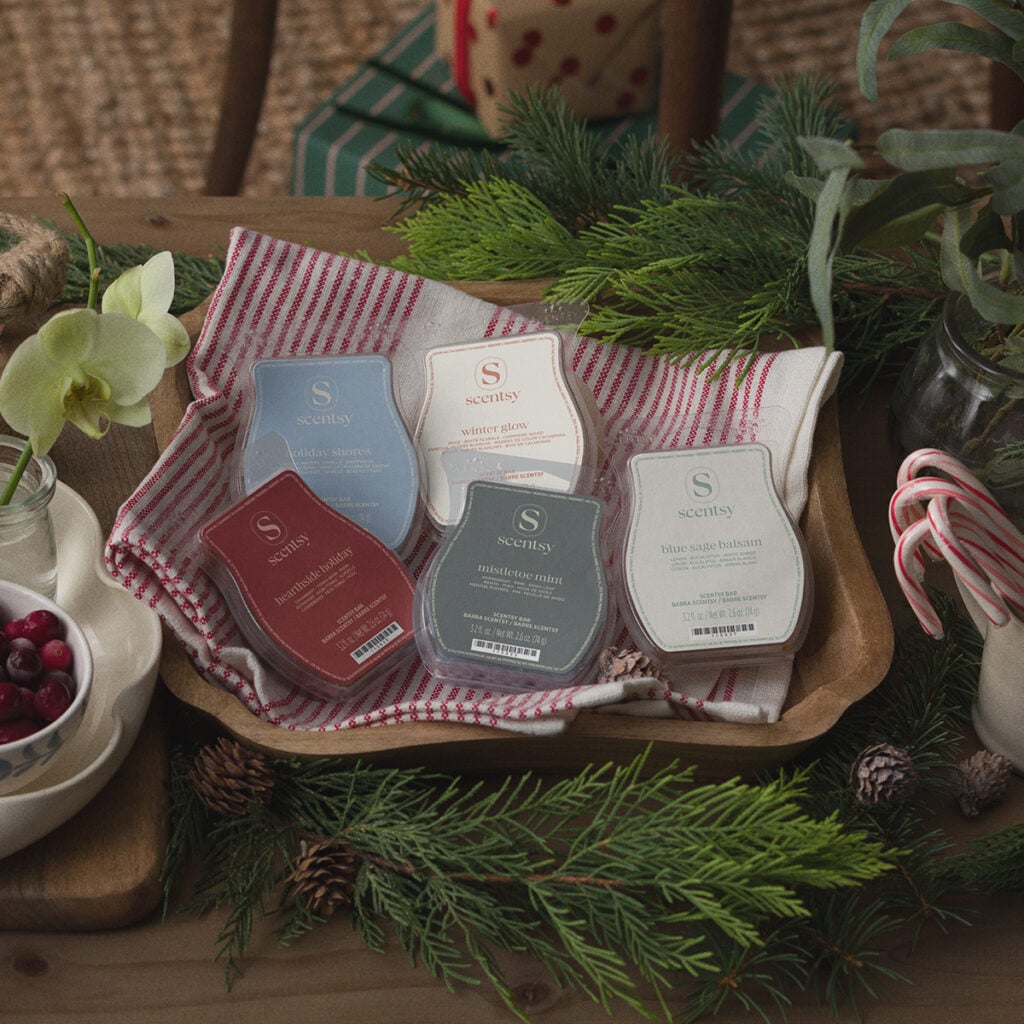 Scentsy 2026 Holiday Wax Collection featuring five seasonal Scentsy Bars styled with evergreen branches, pinecones and candy canes.