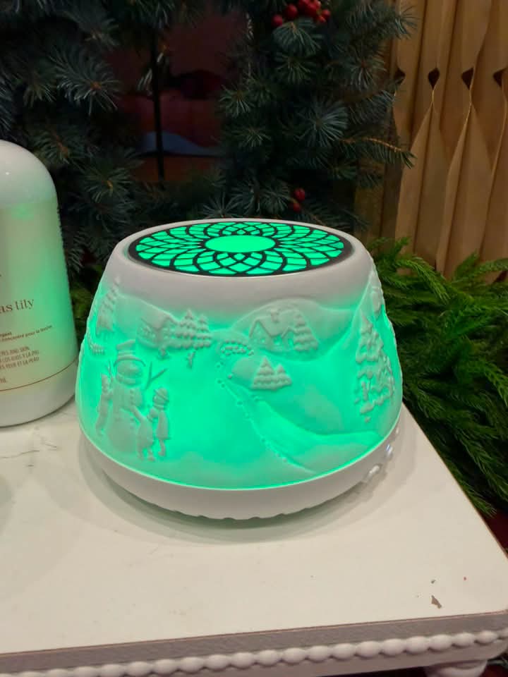 Scentsy Air Quad with Icicle Lane decorative sleeve glowing green with a winter village and snowman scene.