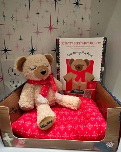 Scentsy Cranberry the Bear Beddy-Bye Buddy with a red holiday scarf and matching cozy bed
