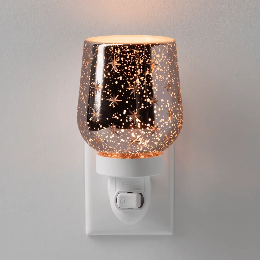 Lit Scentsy Frosted Flurry Mini Warmer with a metallic finish, glowing snowflake and star details.