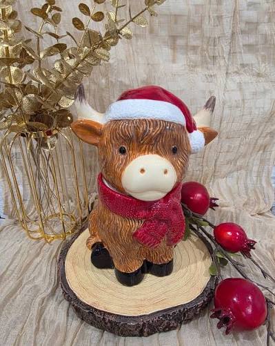 Scentsy Jolly Ol' Saint Moo Warmer shaped like a Highland cow wearing a Santa hat and red scarf.