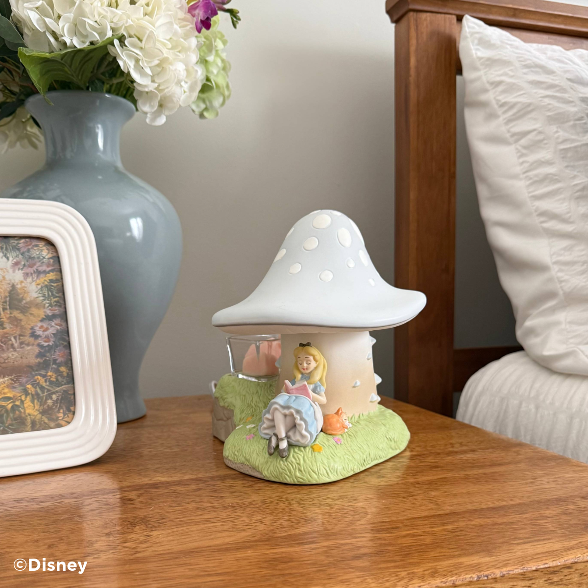 Glowing Disney Alice in Wonderland Down the Rabbit Hole Scentsy Warmer shaped like a blue mushroom, with Alice reading beneath it and a glass dish holding pink wax cubes.