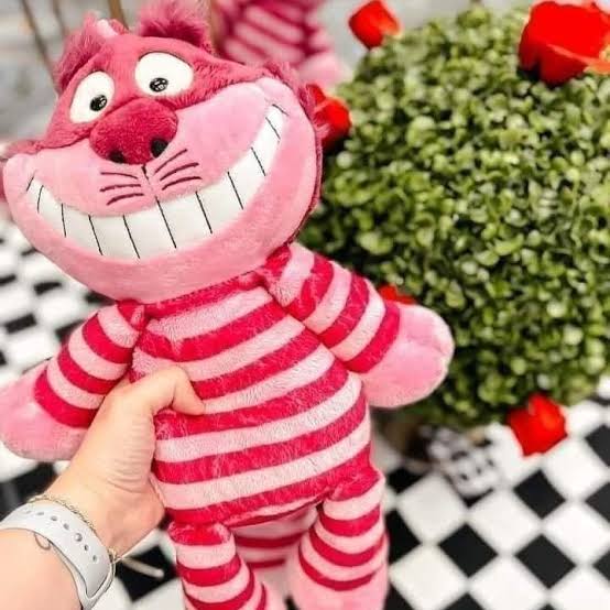 Disney Alice in Wonderland Cheshire Cat Scentsy Buddy plush with pink and magenta stripes, a wide toothy grin and bright eyes.