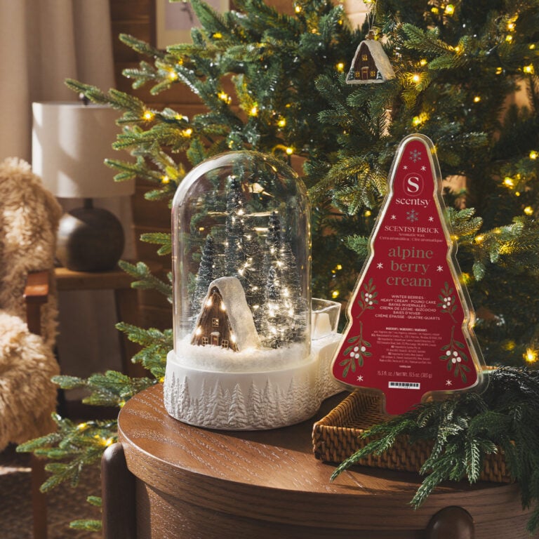 Magic of Winter Scentsy Warmer displayed beside the Alpine Berry Cream Scentsy Brick in front of a decorated Christmas tree with warm white lights.