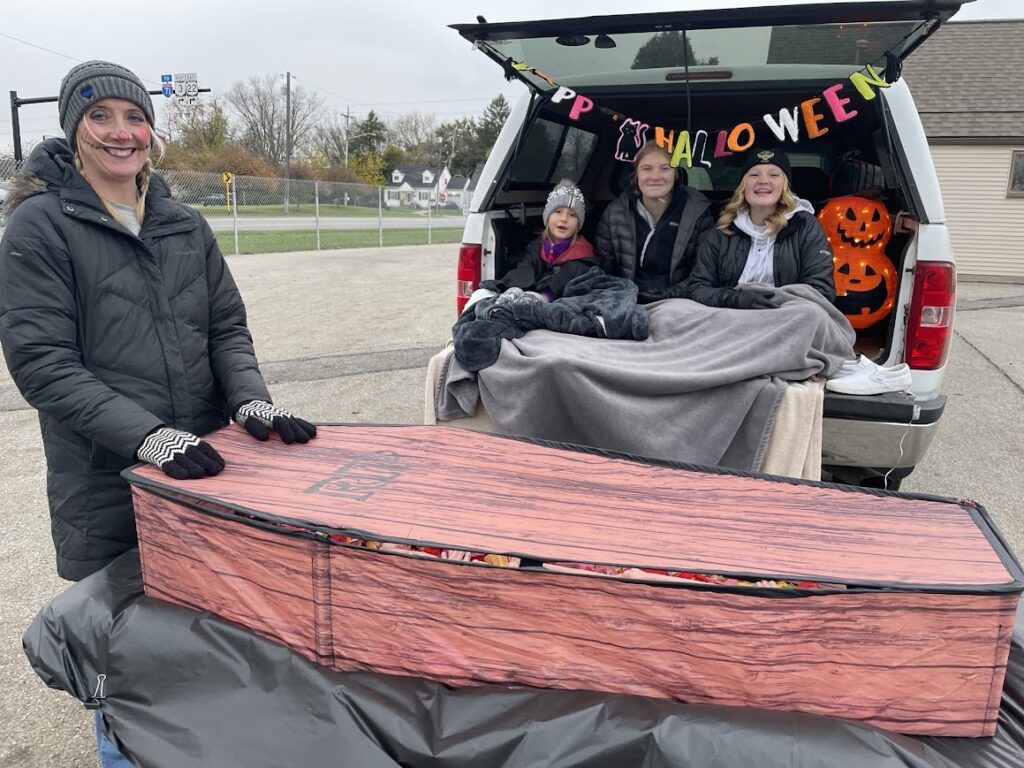 Halloween coffin filled with candy in front of a decorated vehicle at our 2025 Trunk or Treat event.